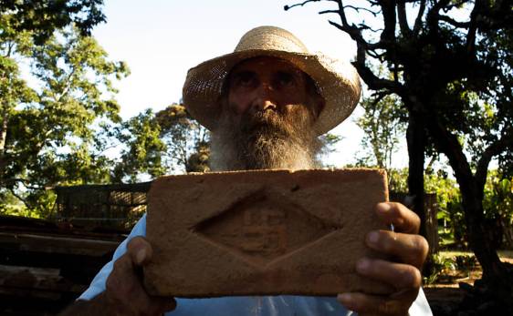 José Ricardo Rosa, 55, conhecido como "Tatão" segurando um tijolo com a suástica nazista; após herdar a fazenda Cruzeiro do Sul na cidade de Campina do Monte Alegre ele encontrou por acaso tijolos com o sinal nazista usados na construção - 