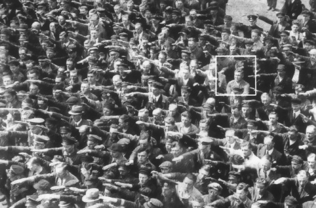 No destaque vemos  August Landmesser sem realizar a saudação nazista, em uma solenidade onde o próprio Hitler estava presente